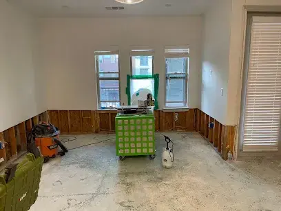 Room with drywall cut away above the baseboard and an air scrubber running
