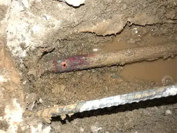 Copper water pipe exposed in wet soil under an opened concrete slab