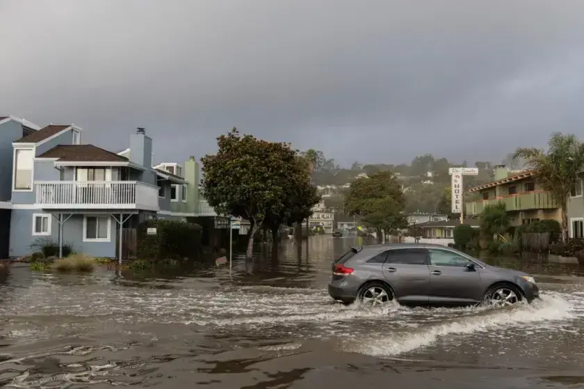 Car pushing through storm runoff on a flooded residential street